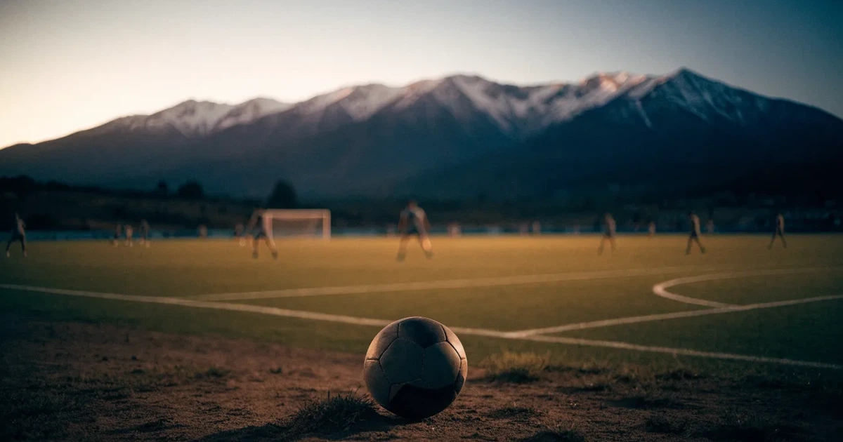 Ein Fussball auf einem staubigen Rasenstück in der Abendsonne, im Hintergrund eine hohe Bergkette
